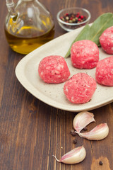 raw meatballs on the dish on wooden background