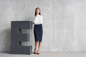 Fototapeta premium Thoughtful girl standing near huge letter