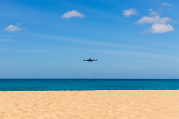 Fototapeta na wymiar Airplane landing above beautiful beach and sea background
