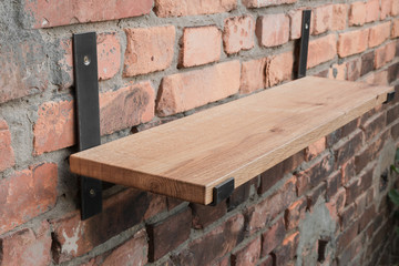 Shelf in wood and metal hanging on a brick wall in loft style