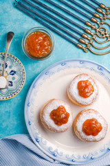 Donuts with jam on a plate and Hanukkah on a turquoise table