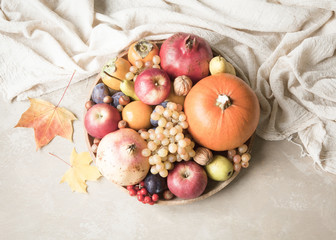 Naklejka na ściany i meble Autumn food concept. Fruits, vegetables and nuts on wooden round tray on light brown background.
