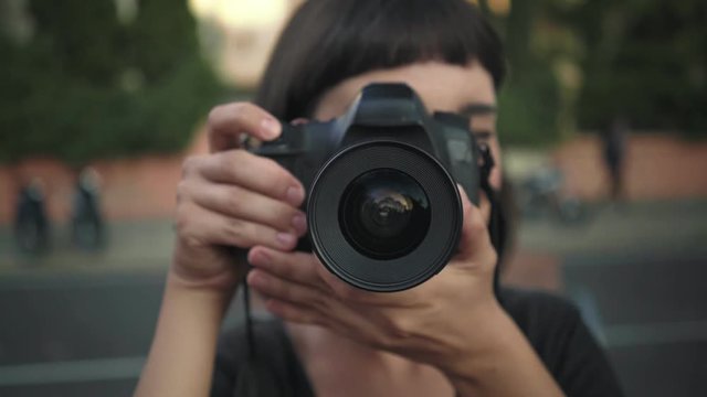 Beautiful young woman with trendy hipster haircut, explores new city or works as freelancer or social media influencer, creates content by making photographs into camera, smiles and giggles