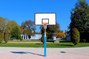 Basketball structure in an outdoor playground surrounded by trees in a park