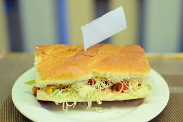 hot sandwich made by a child on a white plate with a sign
