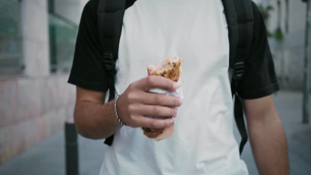 Close up on man holding take away to go sandwich or BLT, eating fast on way to work or school during lunch break, concept food on the go or busy city life, unhealthy snacks