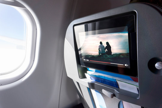 Watching movie on an airplane touch screen. Imaginary film playing on a video player in monitor during long flight. Entertainment service system in aircraft.