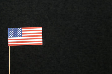 Obraz premium The flag of United States of America (USA) made from paper on wooden stick against dark background with negative copy space for text.