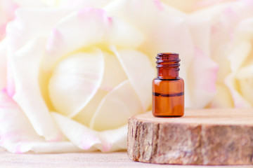 rose essential oil in a glass bottle with fresh rose flowers