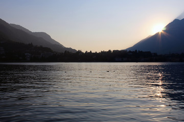 Naklejka na ściany i meble Sunset behind mountains surrounding a flat surface lake under a clear sky