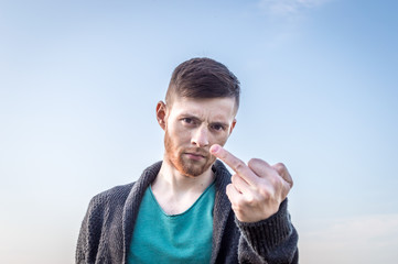 the young man shows a middle finger of a hand
