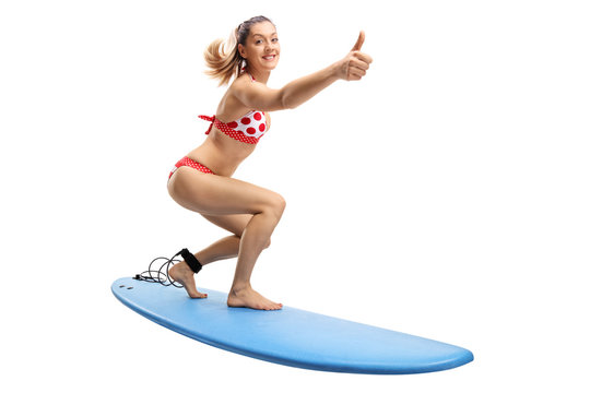 Young woman in a bikini surfing and making a thumb up gesture