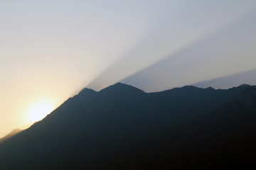 Sunset and rays of light in the sky from behind a mountain