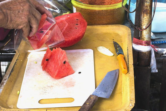 Men's hands are sliced watermelon.