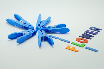 Cloth pin arrangement for flower concept with multicolor wood letter FLOWER word on white background.Creative art with preschool kid at home.