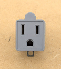 A three to two electrical polarized receptacle plug adapter on a pressed board background.