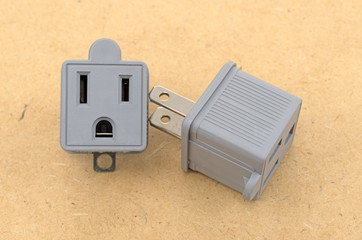 Two three to two electrical polarized receptacle plug adapters on a pressed board background.