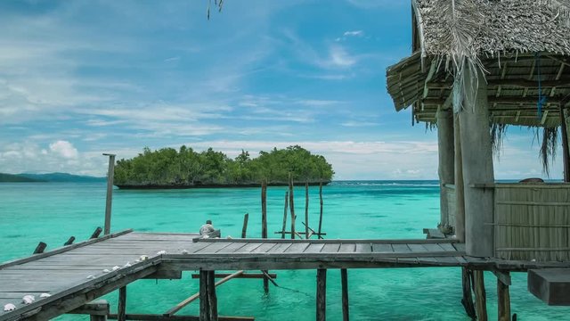 Homstay hut in beautiful blue lagoone and some island in background. Kordiris Homestay on Gam Island, West Papua, Raja Ampat, Indonesia