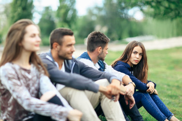 Young people sitting on lawn in park closeup