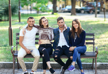 Four women and men sitting on bench in embrace