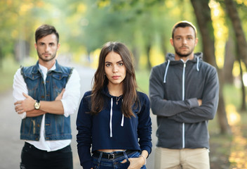 Fototapeta premium Beautiful young woman and two men behind her
