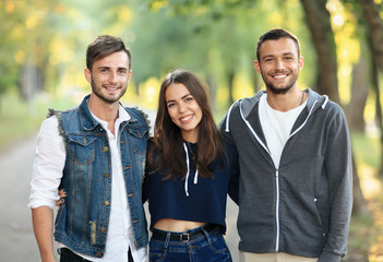 Three young friends hugging, smiling and looking at camera