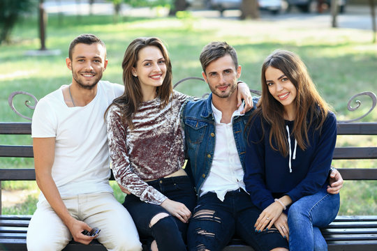 Four women and men sitting on bench in embrace