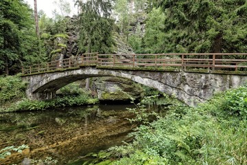 Fototapeta na wymiar Old stony bridge over the clean river