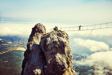 Gardinen Woman is walking along a suspension bridge over an abyss. © 6okean