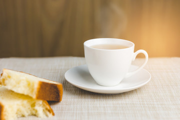 Cup of tea with bread for breakfast on wooden background