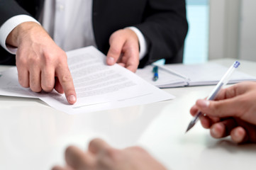 Signing a contract or agreement. Banker or lawyer showing client the line for autograph in a...