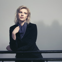 Young fashion woman in classic black coat in a fog outdoor