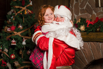 Santa Claus holds on hands happy little girl.