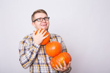 portrait of a young farmer holding a pumpkins on a light background studio