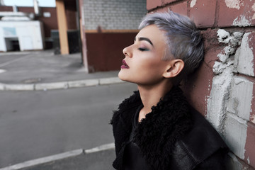 Young beautiful fashion girl shooting outdoors near brick wall at home