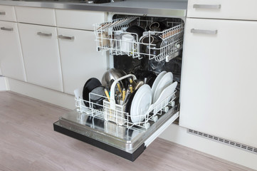 Open dishwasher with clean plates, cups and dishes