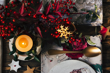 Candle lit on the Christmas table, surrounded by festive decoration