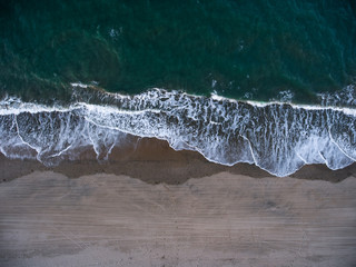 Fototapeta na wymiar Waves rolling in on beach drone