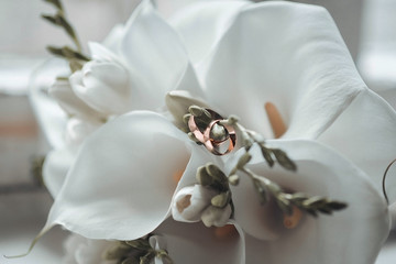 Beautiful bridal bouquet of bride with wedding rings on lilies, close-up.