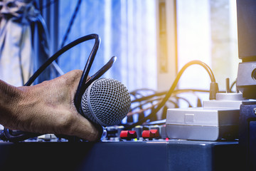 Man's hands control the sound. The microphone and the audio mixer.