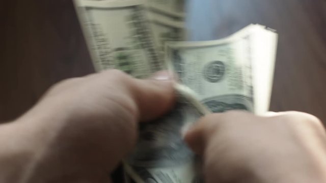 Close-up of man's hands counting hundred dollar bills