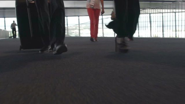 Female and male legs walking on carpeted airport floor with suitcase, departure