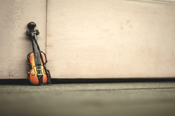Music passion and hobby concept, violin miniature over wooden wall with retro color tone.copy space on the right for text