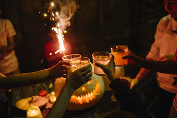 Group of friends in the party with pumpkin, candies and soft drinks