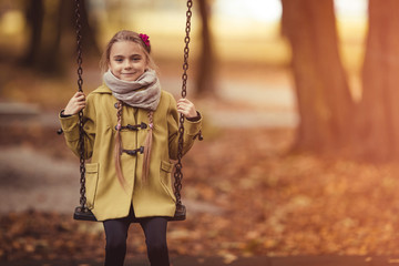 Happy young girl at the swing. Autumn theme.