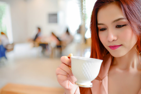 Portrait of beautiful woman holding a cup of coffee in her hand on blur background coffee shop, she drink coffee every day