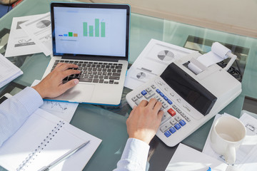 Business man using calculator and laptop for data alalysis at work office
