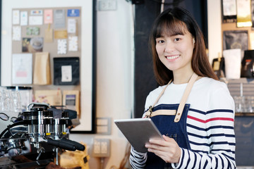 Young asian woman, barista, using tablet to get coffee order at cafe counter background, food and drink concept