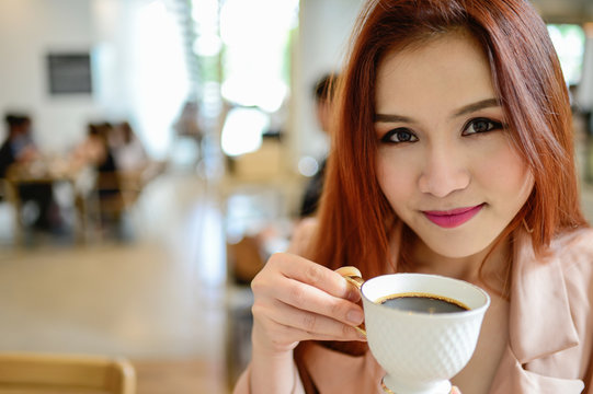 hand of beautiful woman holding a cup of coffee in blur background coffee shop, she drink coffee in the morning