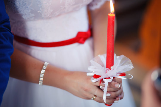 Bride in beautiful dress with lighted candles on wedding ceremony in church